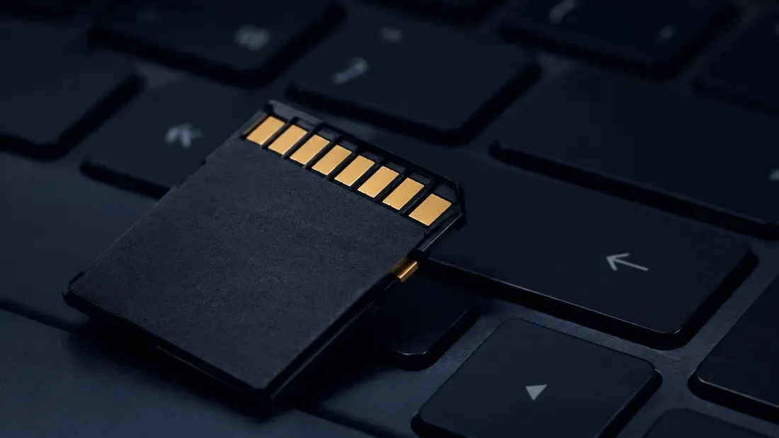 Memory card with exposed gold contacts resting on a laptop keyboard